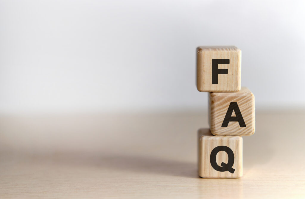 Three wooden blocks stacked vertically, each with a black letter spelling "FAQ" from top to bottom, placed on a light-colored surface with a plain, neutral background.